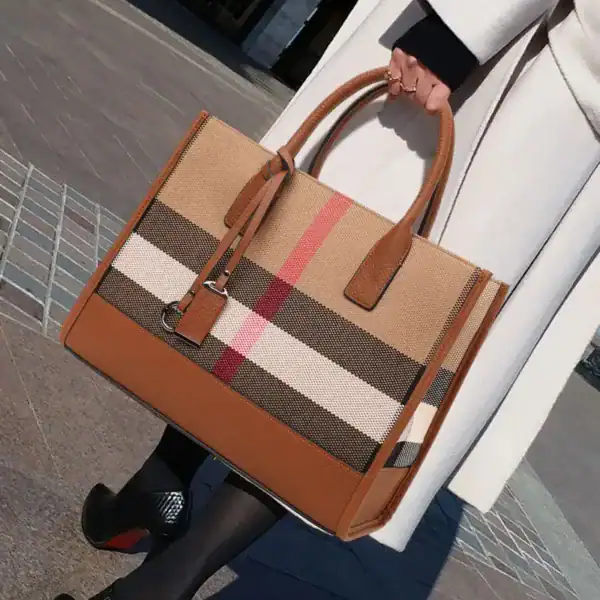 Beige rutig handväska med bruna handtag och klassiskt rutigt mönster.