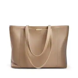 Beige shoppingväska med långt handtag och guldaktig snabb.