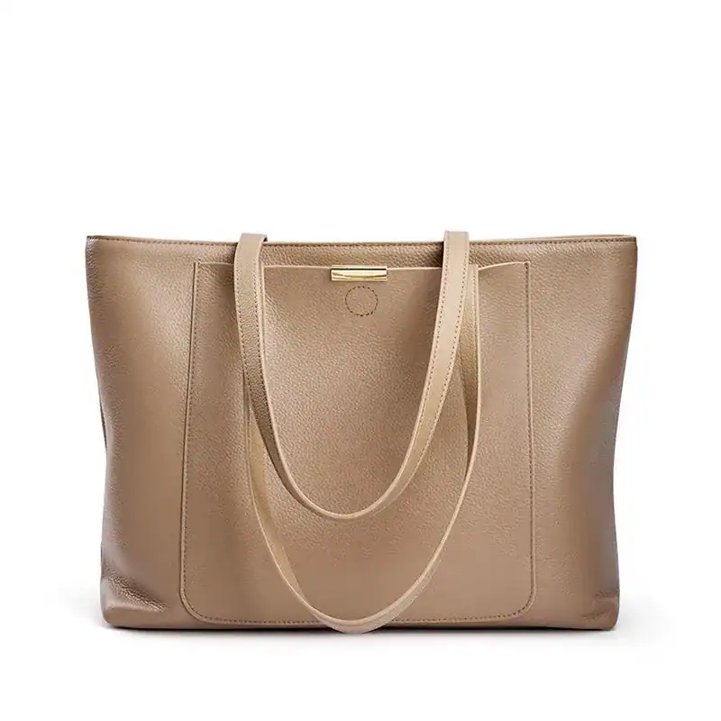 Beige shoppingväska med långt handtag och guldaktig snabb.
