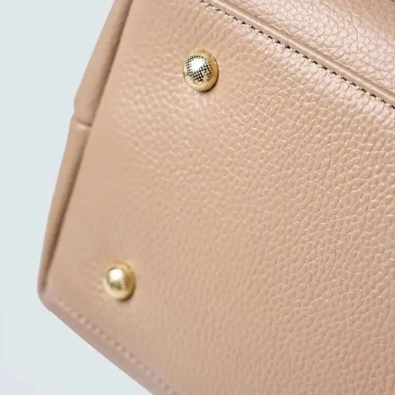 Beige shoppingväska med guldpläterade knappar och texturerat läder.