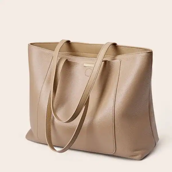 Beige shoppingväska i läder med långa handtag och minimalistisk design.