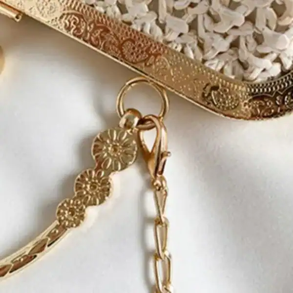 Beige stråclutch med guld detaljer och blomsterformad kedja.