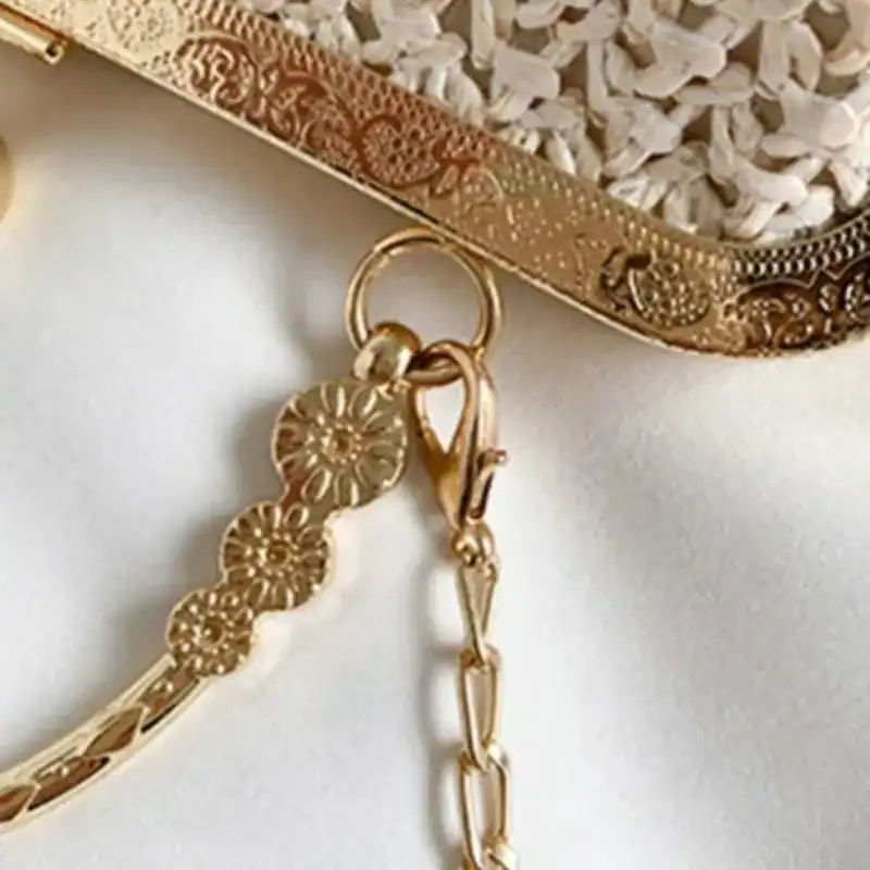 Beige stråclutch med guld detaljer och blomsterformad kedja.