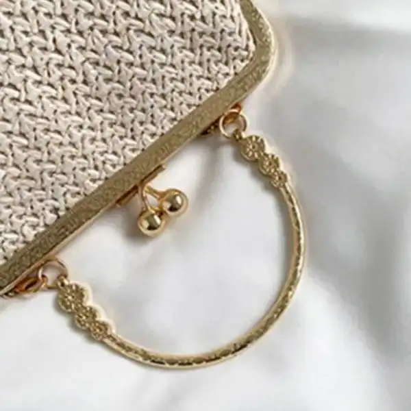 Beige stråclutch med guld handtag och detaljer.