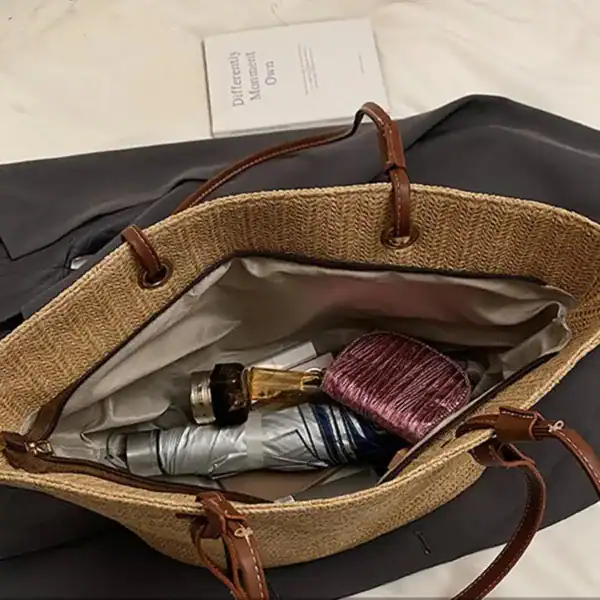 Beige stråkorg med bruna handtag och innehåll som paraply och frisyrborste.