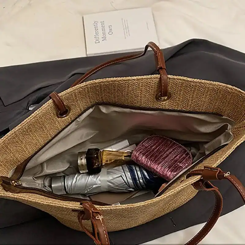 Beige stråkorg med bruna handtag och innehåll som paraply och frisyrborste.