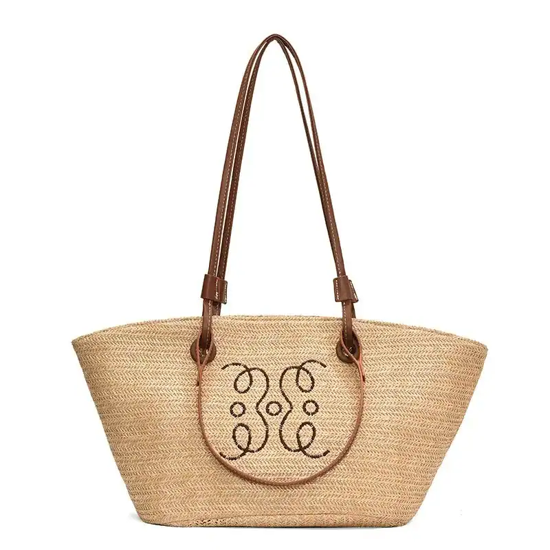 Beige stråkorg med bruna handtag och dekorativt mönster.