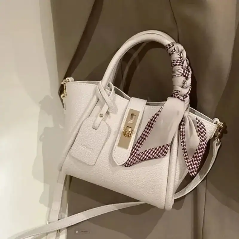 Beige axelväska med sidenscarf och guldaktig snäcka.
