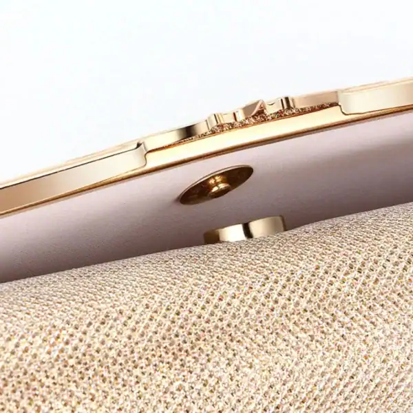 Beige vävd clutch med guldram och knapp, närbild av textur och detaljer.
