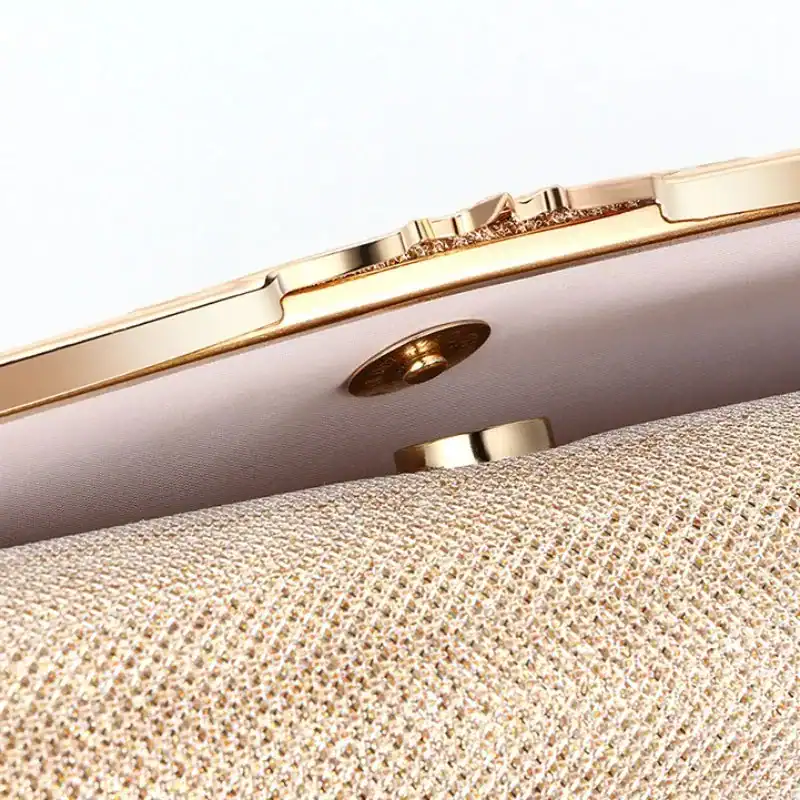 Beige vävd clutch med guldram och knapp, närbild av textur och detaljer.