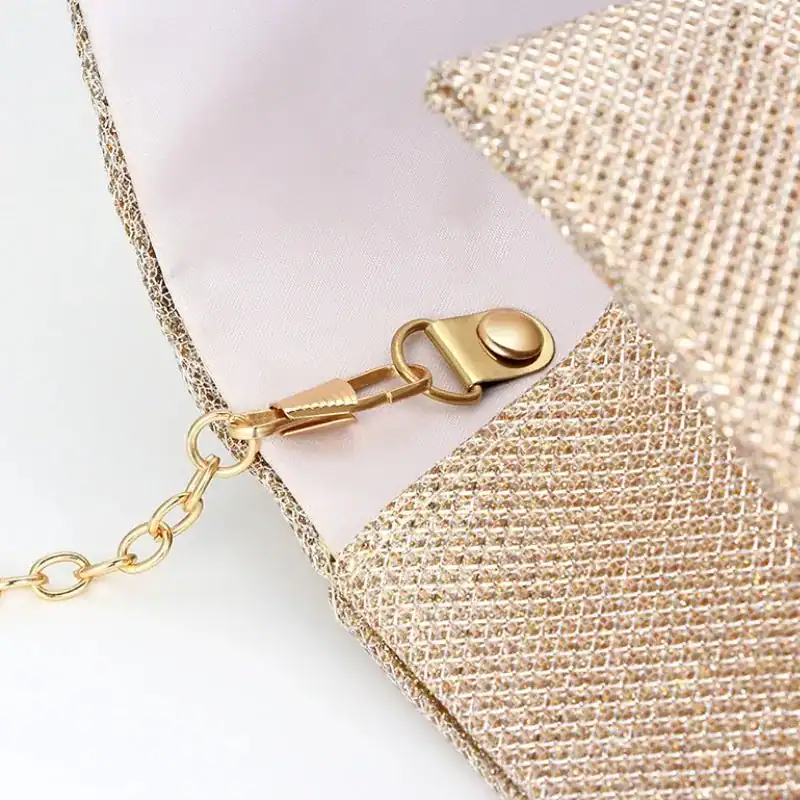 Beige vävd clutch med guld fäste och kedja.