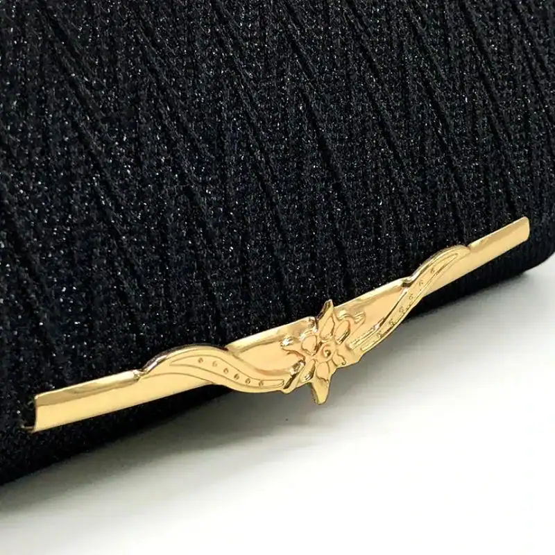 Svart vävd clutch med guldaktig blomma på snäckskalformad knapp.