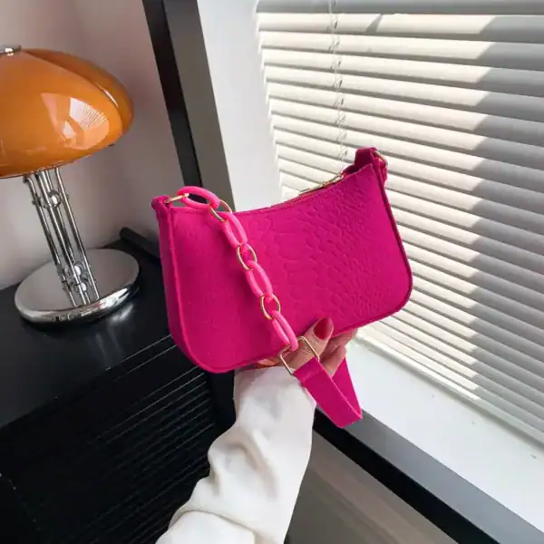 Blå axelremsväska i rosa, med kedjehandtag och texturerad yta.