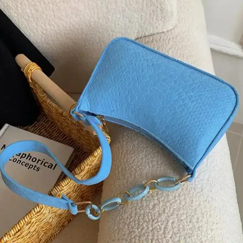Blå axelremsväska med kedjehandtag och texturerad yta.