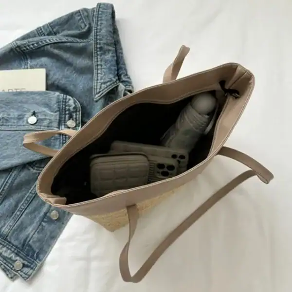 Brun beige flätad shoppingväska med innehåll, jeans och mobil.