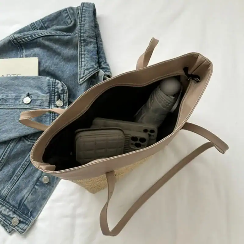 Brun beige flätad shoppingväska med innehåll, jeans och mobil.