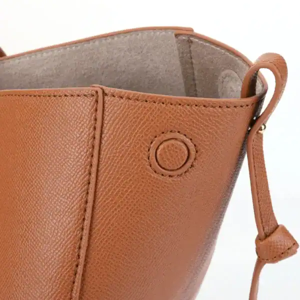 Brun halvmånsformad shoppingväska med texturerat läder och detaljerad sömmar.