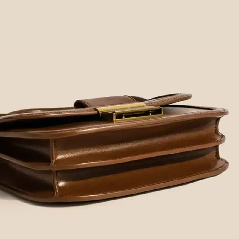Brun liten axelremsväska med metallficklås och elegant design.