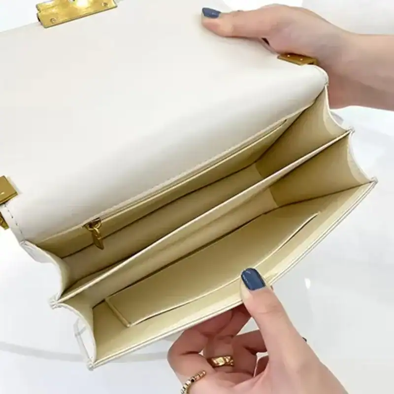 Brun liten axelremsväska med inre fickor och guldpläterade detaljer.