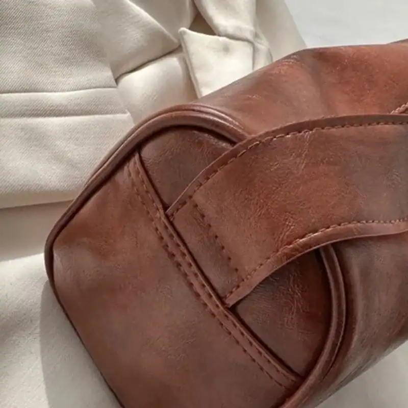 Brun liten axelväska i läder med detaljerad sömn och elegant design.