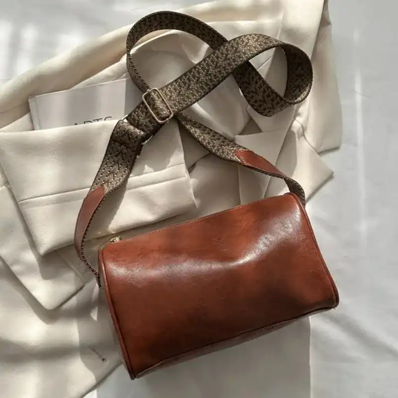 Brun liten axelväska med mönstrad axelrem, läder, mode, trendig.