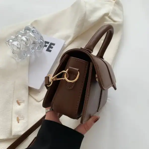 Brun liten väska med lock, handtag och axelrem, modeaccessoarer för kvinnor.