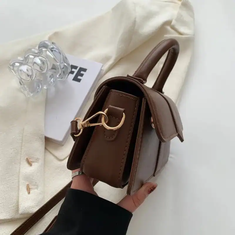Brun liten väska med lock, handtag och axelrem, modeaccessoarer för kvinnor.