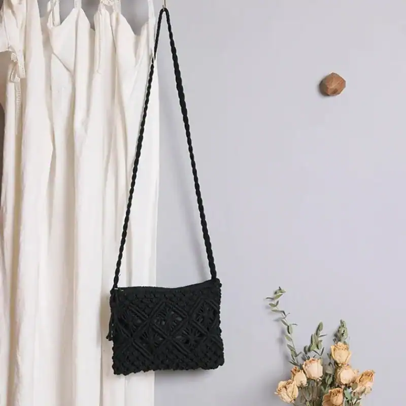 Brun makramé clutch med lös bälte, hängande mot vit gardin och blommor.