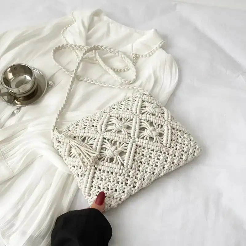 Brun makramé clutch med tasslar och silverfärgad axelrem.