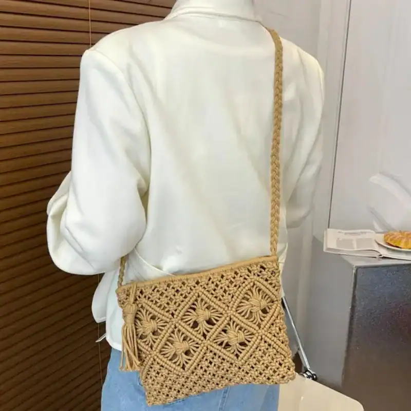 Brun makramé clutch med tassar och broderad mönster, bärt som axelväska.
