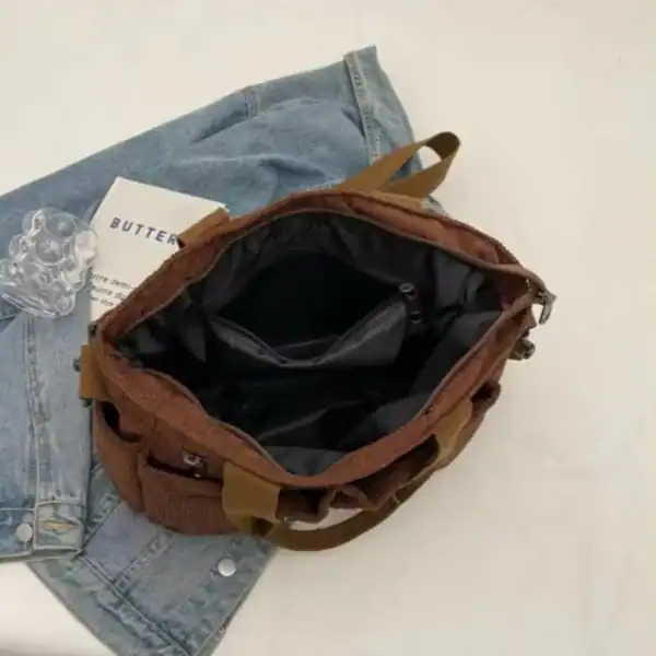 Brun manchester hinkväska med svart inre och jeans i bakgrunden.