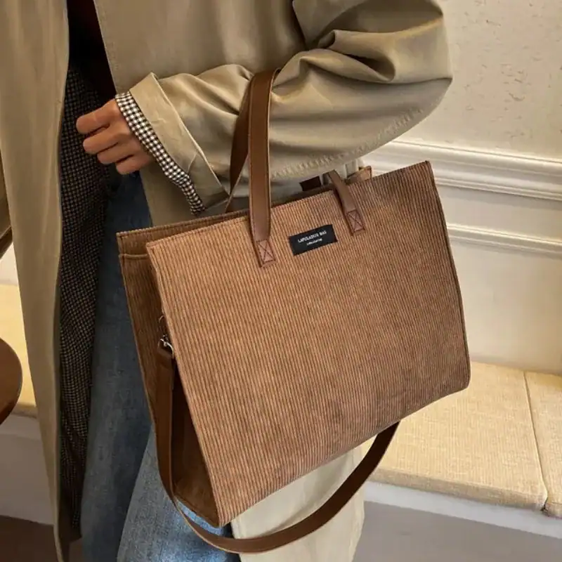 Brun manchester shoppingväska i corduroy med läderhandtag och plåtlogga.