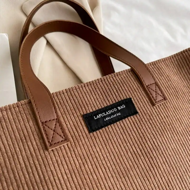 Bruna shoppingväska med läderhandtag och etikett, passande för vardag och shopping.