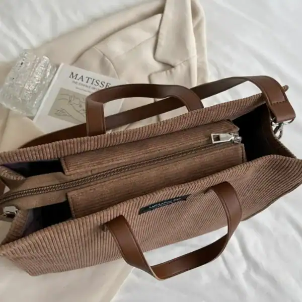 Brun corduroy shoppingväska med läderhandtag och dragkedja.
