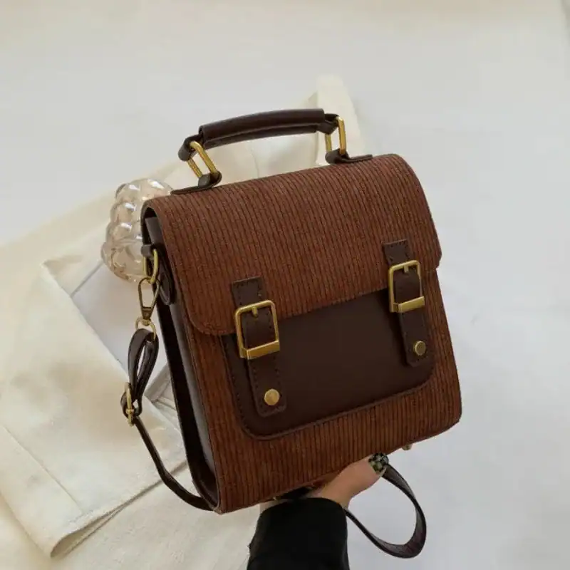 Brun manchesterryggsäck med guldtonade spänare och handtag.