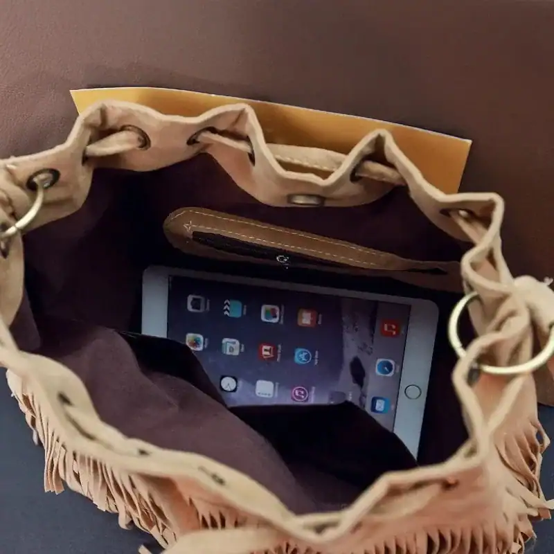 Brun mocka hinkväska med fransar, innehåller tablet och plånbok.