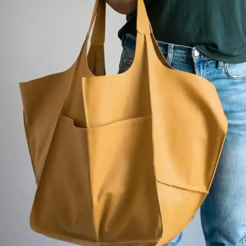 Brun mocka shoppingväska med framsida fickor och höga handtag.