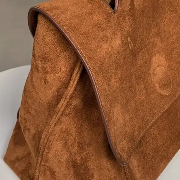 Brun mockaväska med lock, detalj på textil och snitt.