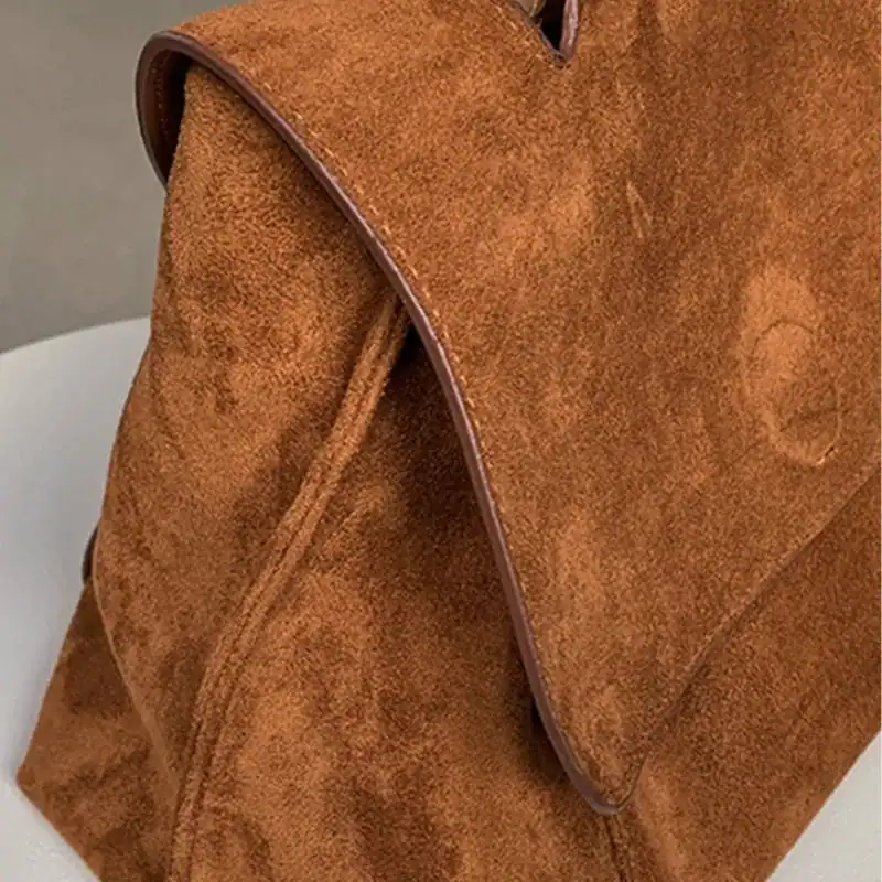 Brun mockaväska med lock, detalj på textil och snitt.