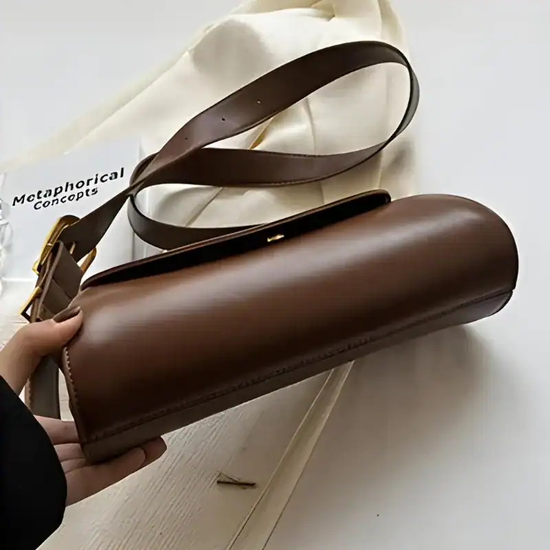 Brun rullformad väska med axelrem, elegant och minimalistisk design.