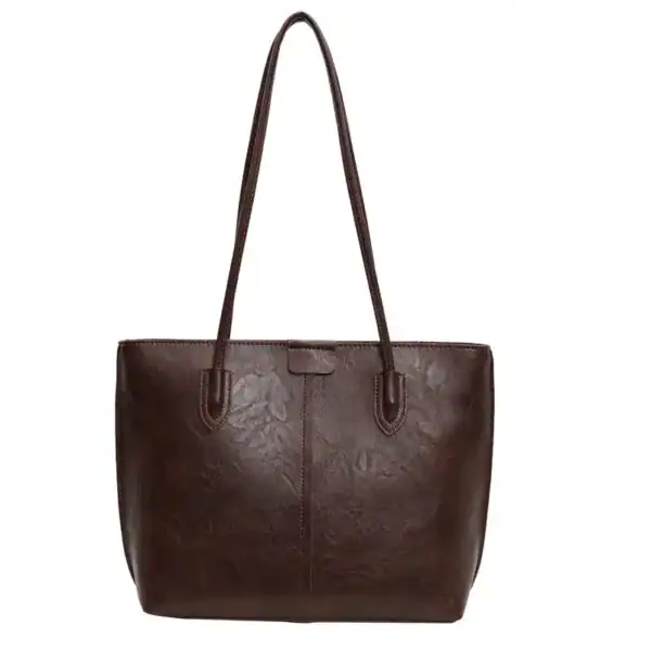 Brun shopper väska i läder med texturerat yta och långt handtag.