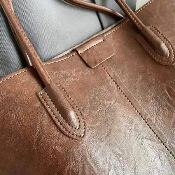 Brun shopper väska i läder med detaljerad sömnad och handtag.