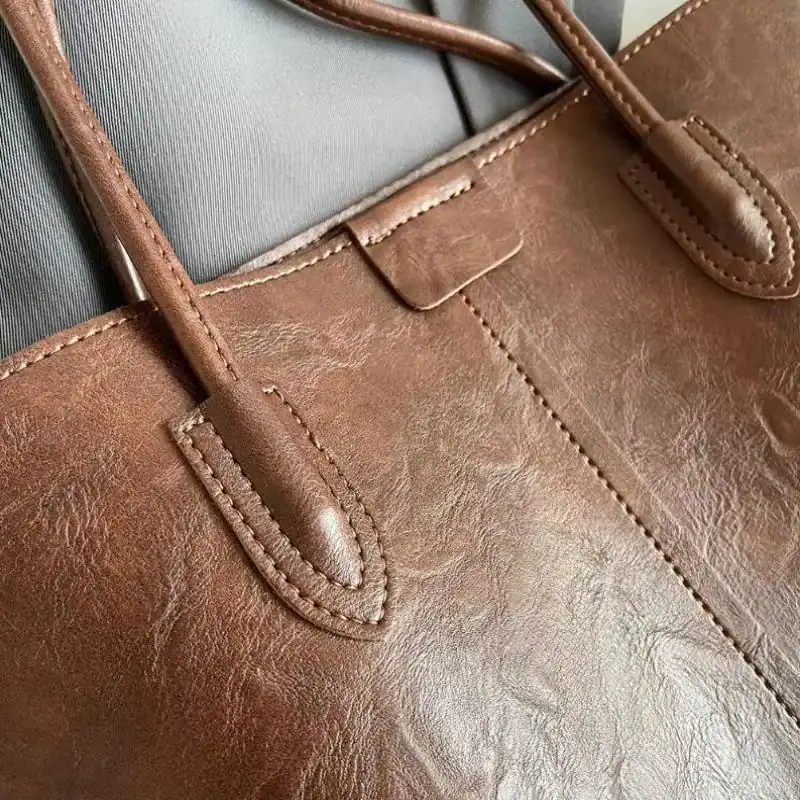 Brun shopper väska i läder med detaljerad sömnad och handtag.