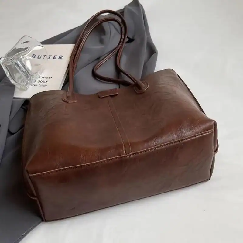 Brun shopper väska i läder med handtag, stilrent och trendig för vardag.