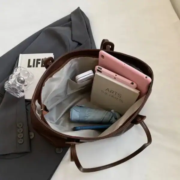 Brun shoppingväska med innehåll, mobil, bok och paraply.