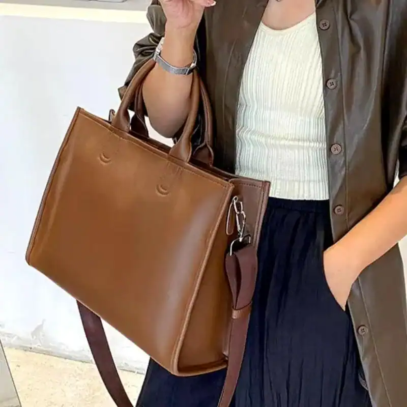 Brun shoppingväska med axelrem och handtag, lämplig för vardag och jobb.
