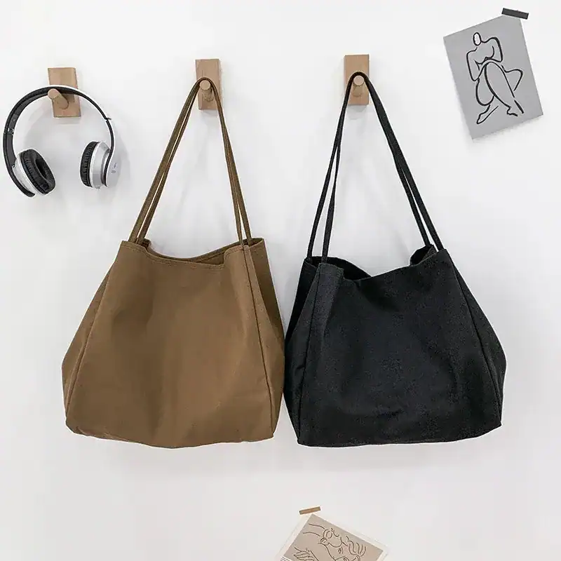 Brun tygshopper och svart tygshopper hängande på vägg, minimalistiskt inredning.