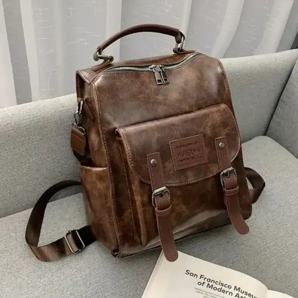 Brun vintage ryggsäck dam, läderliknande material, skuldraslinga och handtag.