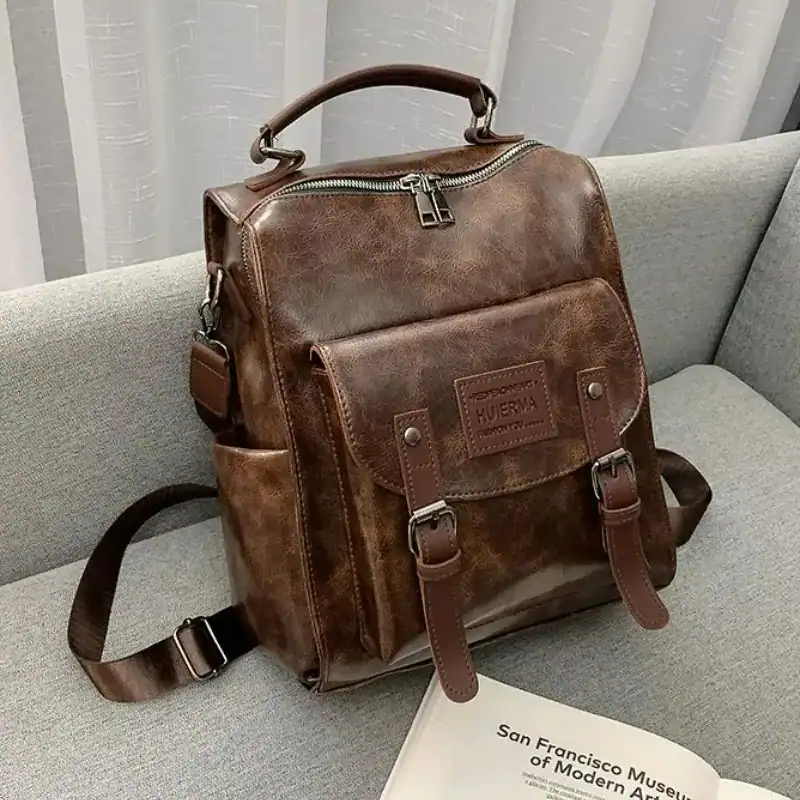 Brun vintage ryggsäck dam, läderliknande material, skuldraslinga och handtag.
