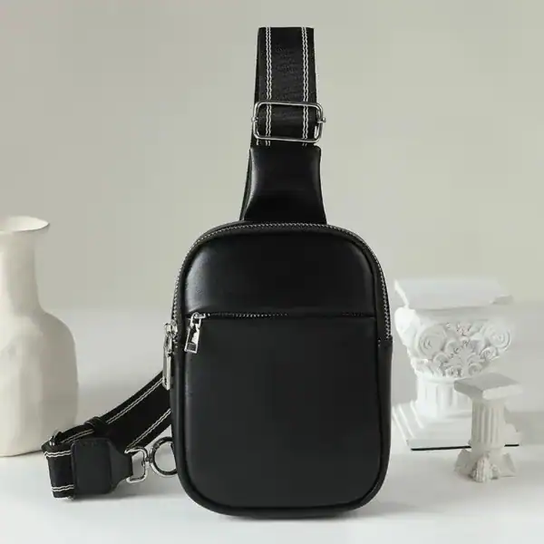 Svart cognac bröstväska med vit kontraststitching och justerbar axelrem.